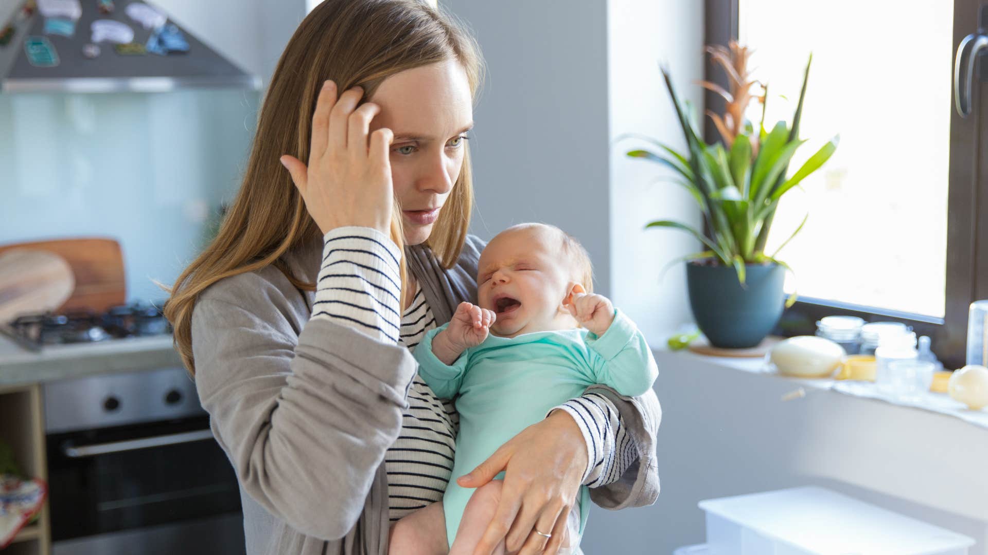 woman grappling with physical struggles while holding her baby