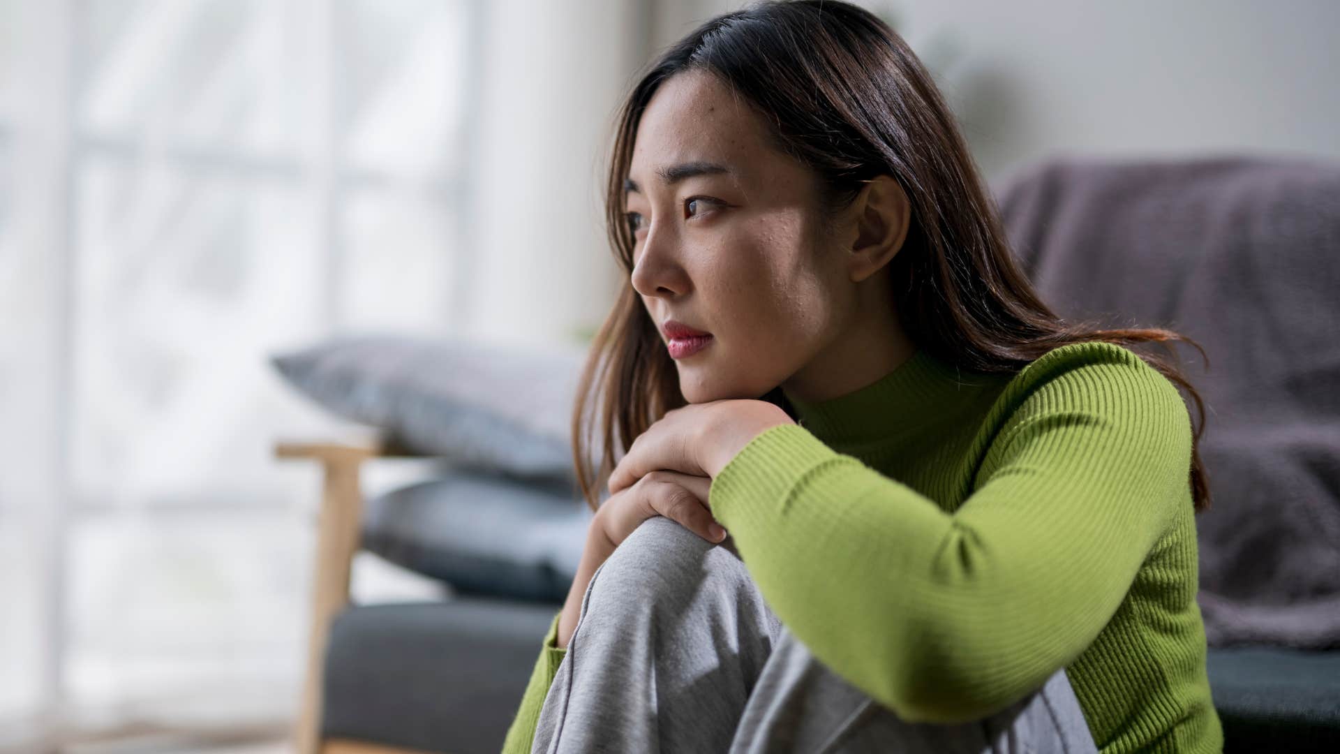 Overstimulated woman sitting on the floor in her living room.