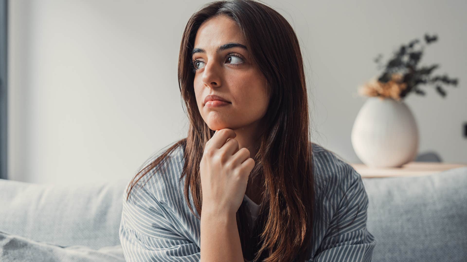 Woman who craves stillness looking out a window from her couch.