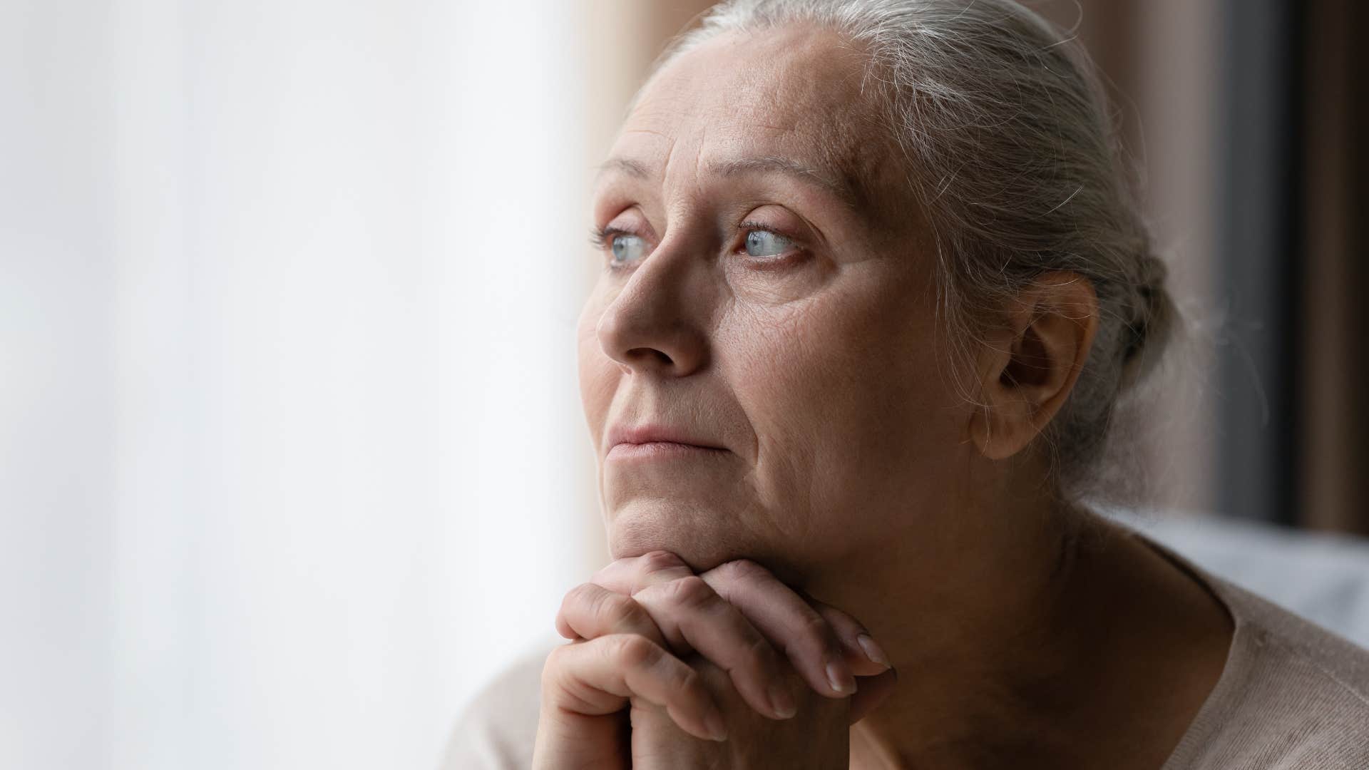Woman who's tired of caring for everyone else looking out a window.