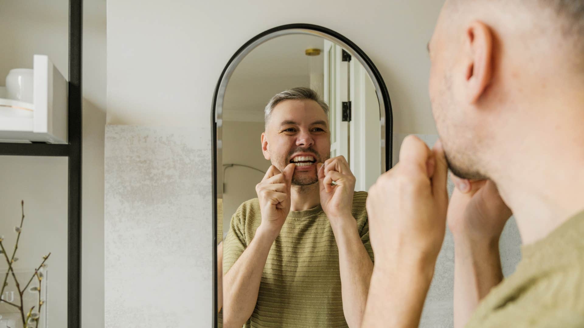 a man flosses his teeth before brushing them