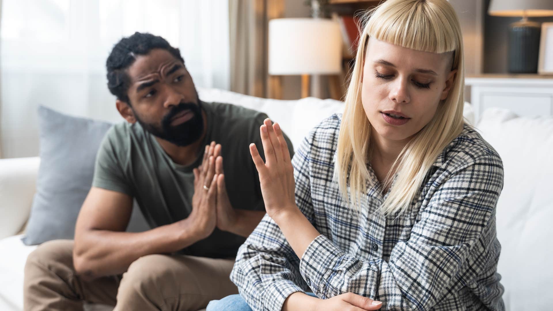 Woman turned away from her upset partner shifting blame.