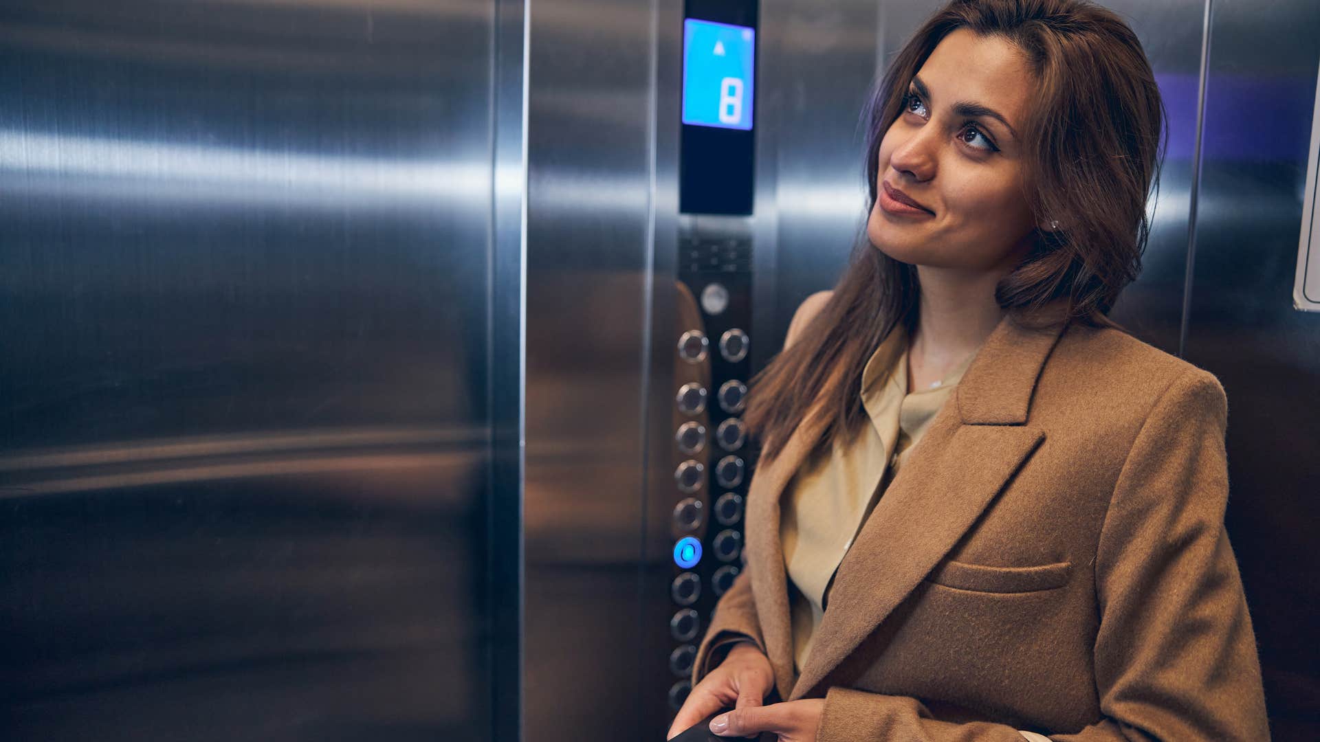 woman smiling in an elevator letting people off
