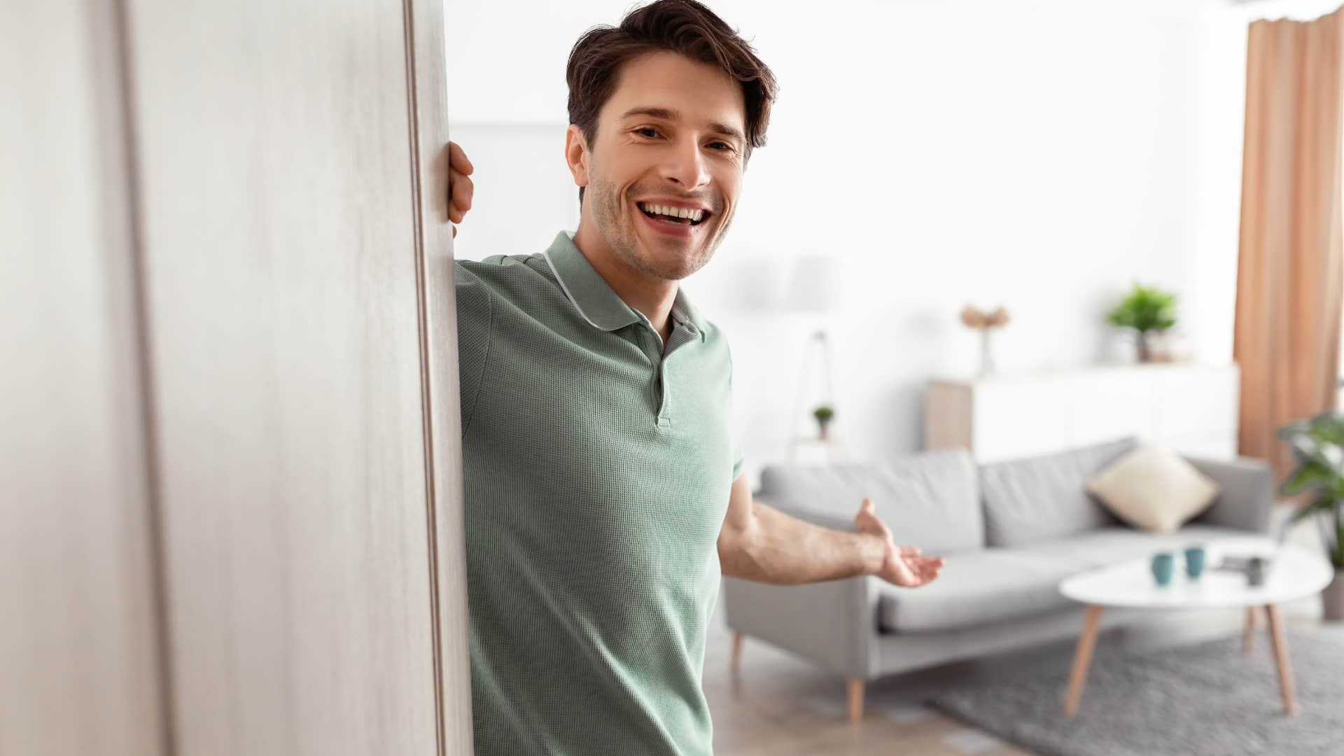 man smiling and holding the door to let someone in