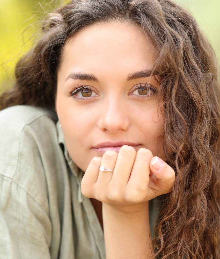 Woman looks at camera with ring on finger.