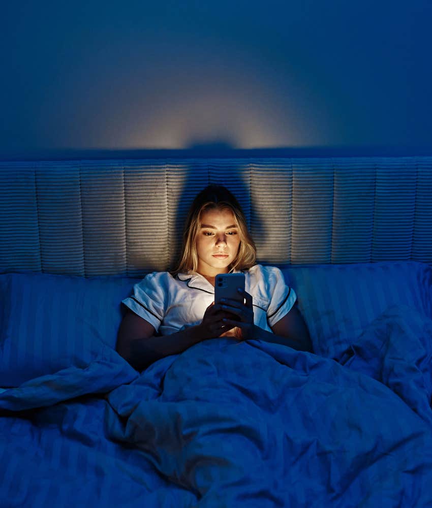 Woman uses phone in bed.