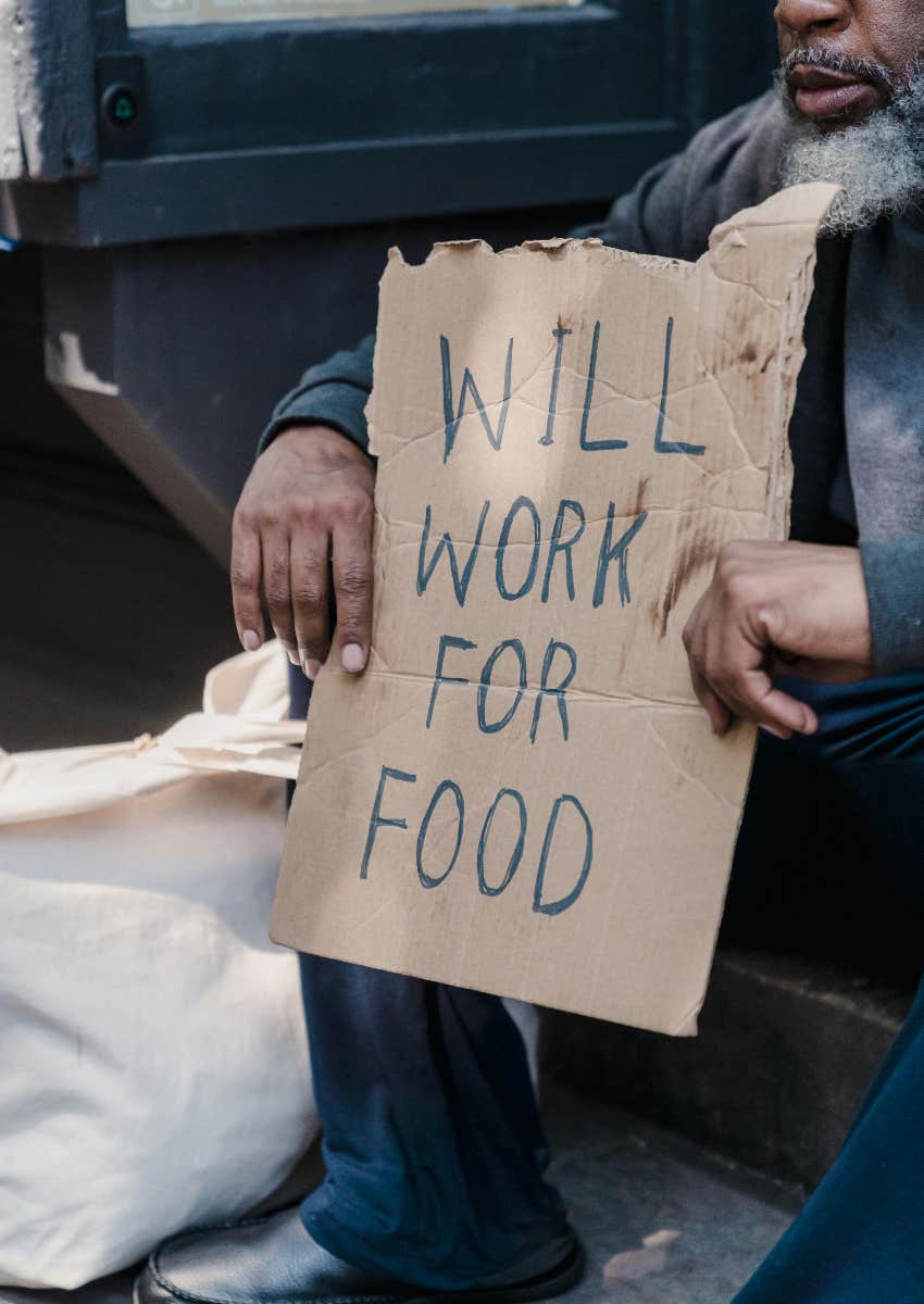 homeless man holding a sign that says "will work for food"
