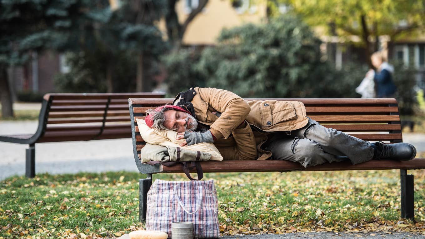 homeless man sleeping on a public bench outside