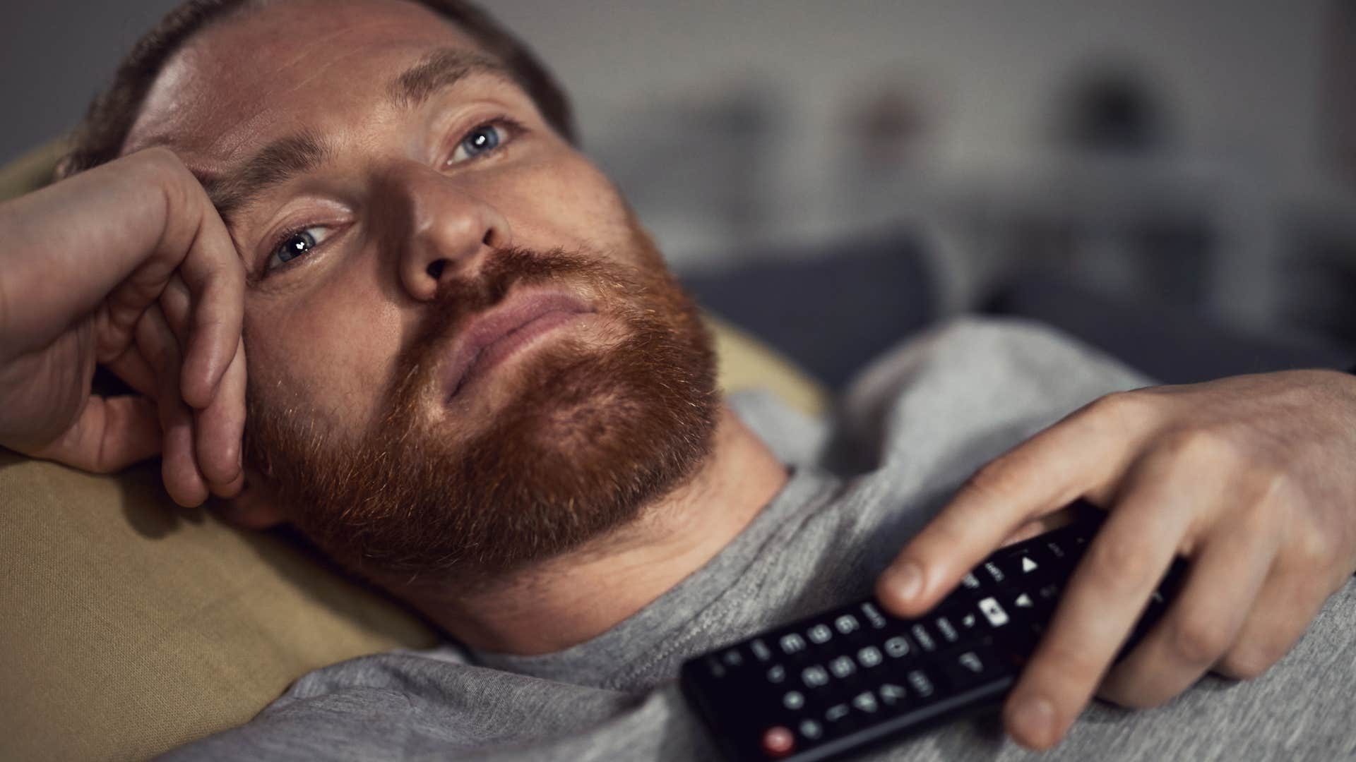 Man engaging with constant mindless entertainment on the couch.