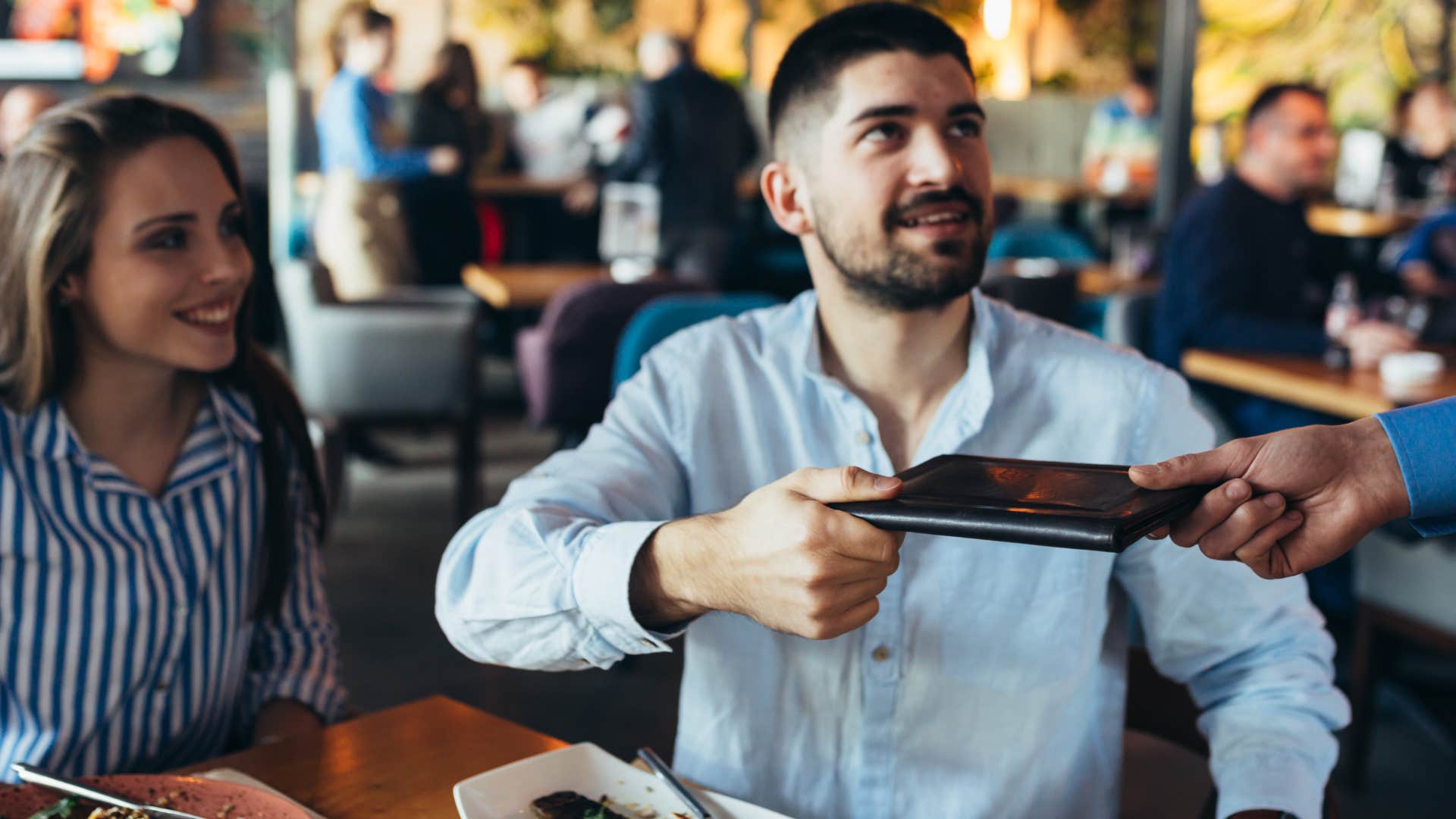 Man who's eating out regularly paying for the bill.