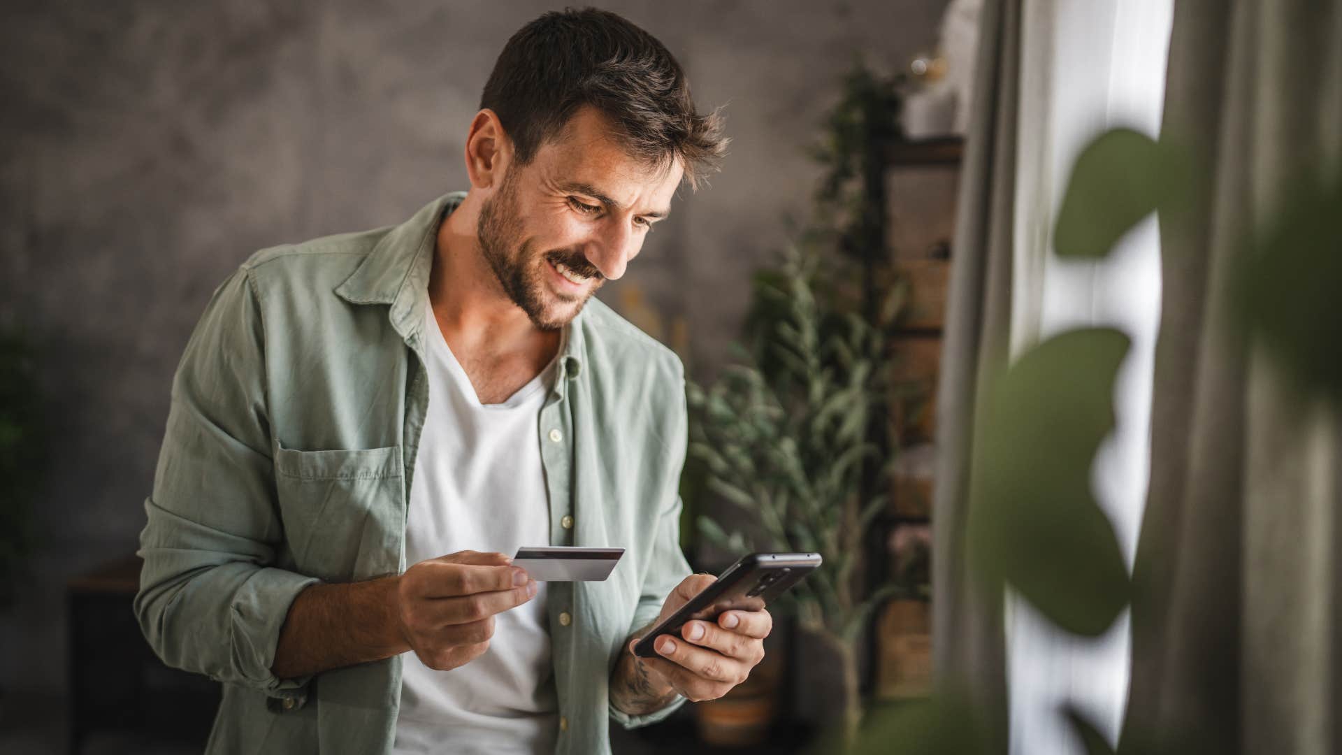 Man who impulsively online shops looking at his phone.