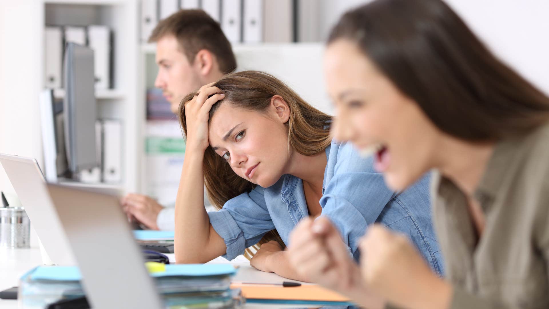 jealous narcissist woman looking at overachieving co-worker