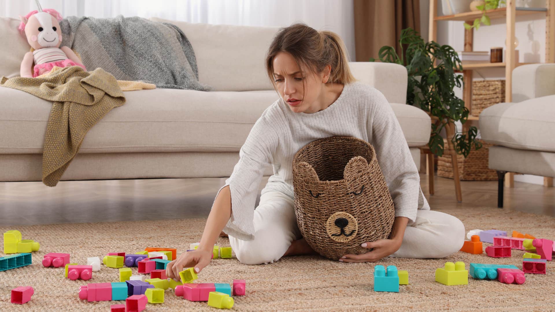 woman cleaning up toys and clutter in living room