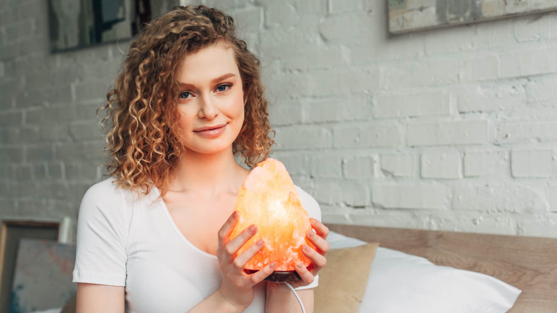 woman holding a himalayan salt lamp for clearing negative energy