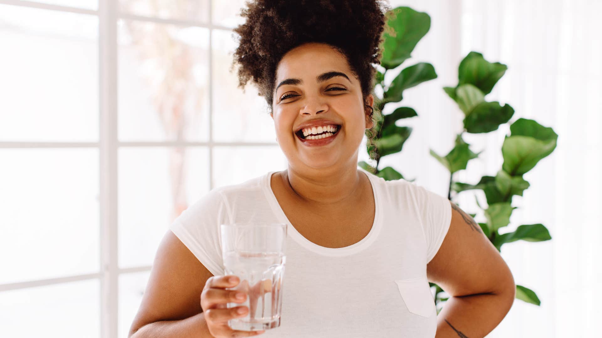 woman holding a glass of salt water to ward off bad energy