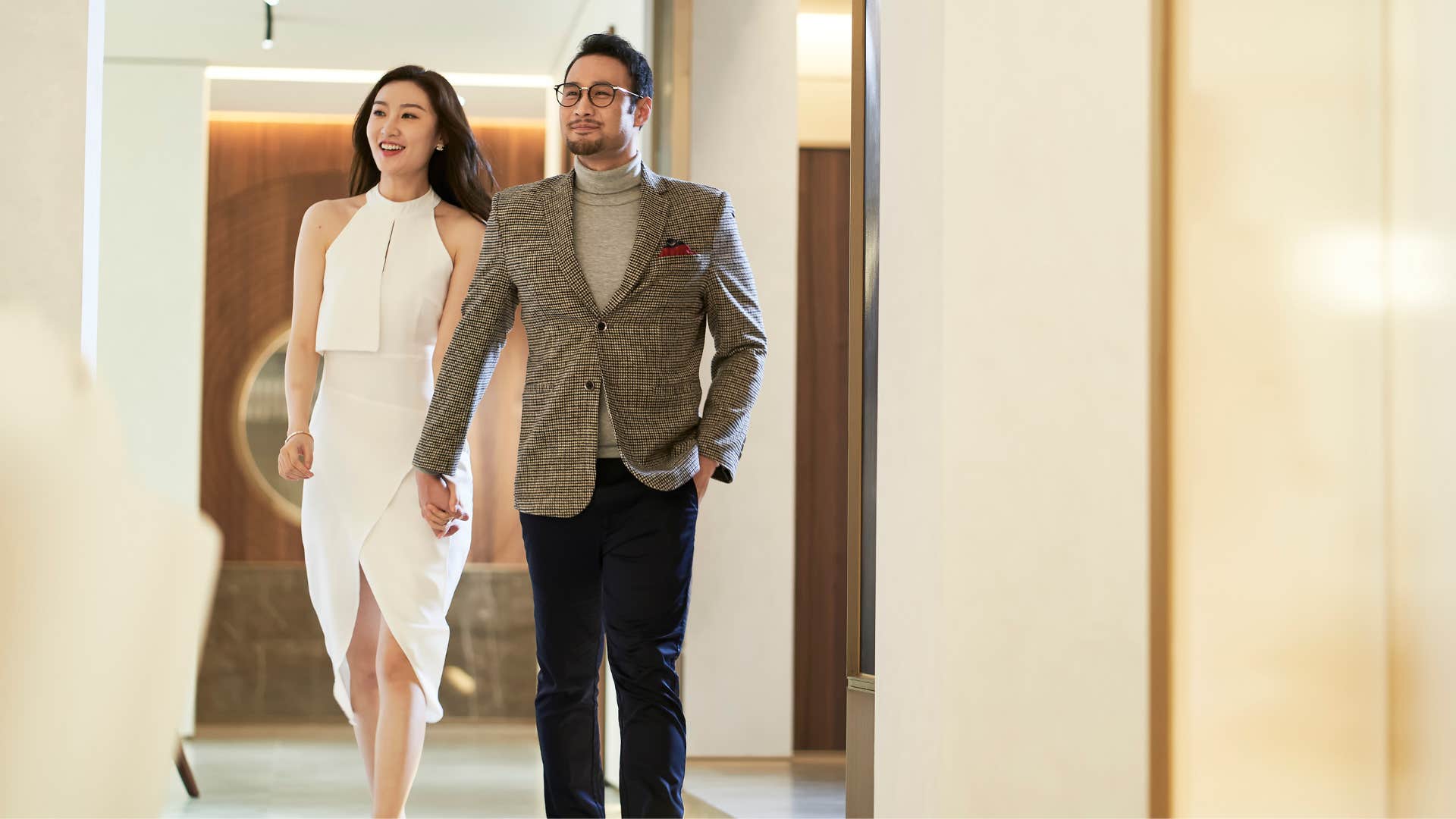 couple in nice clothing holding hands and checking out overpriced luxury apartments