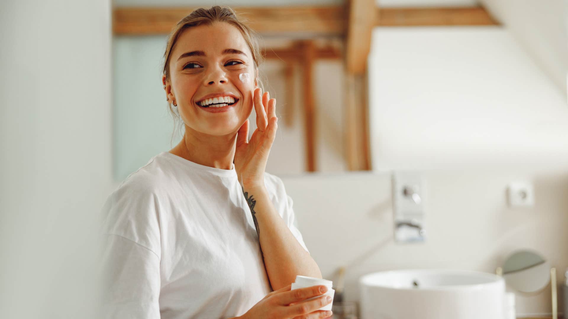 woman using beauty product as she smiles