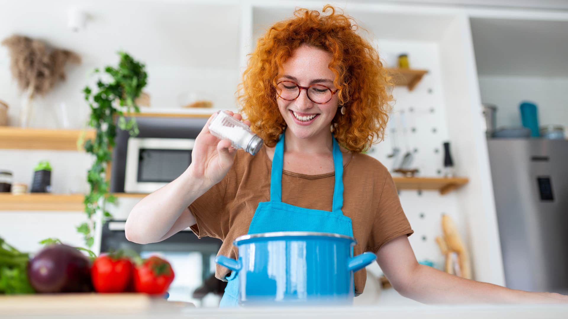 woman adding spices to cooking pot