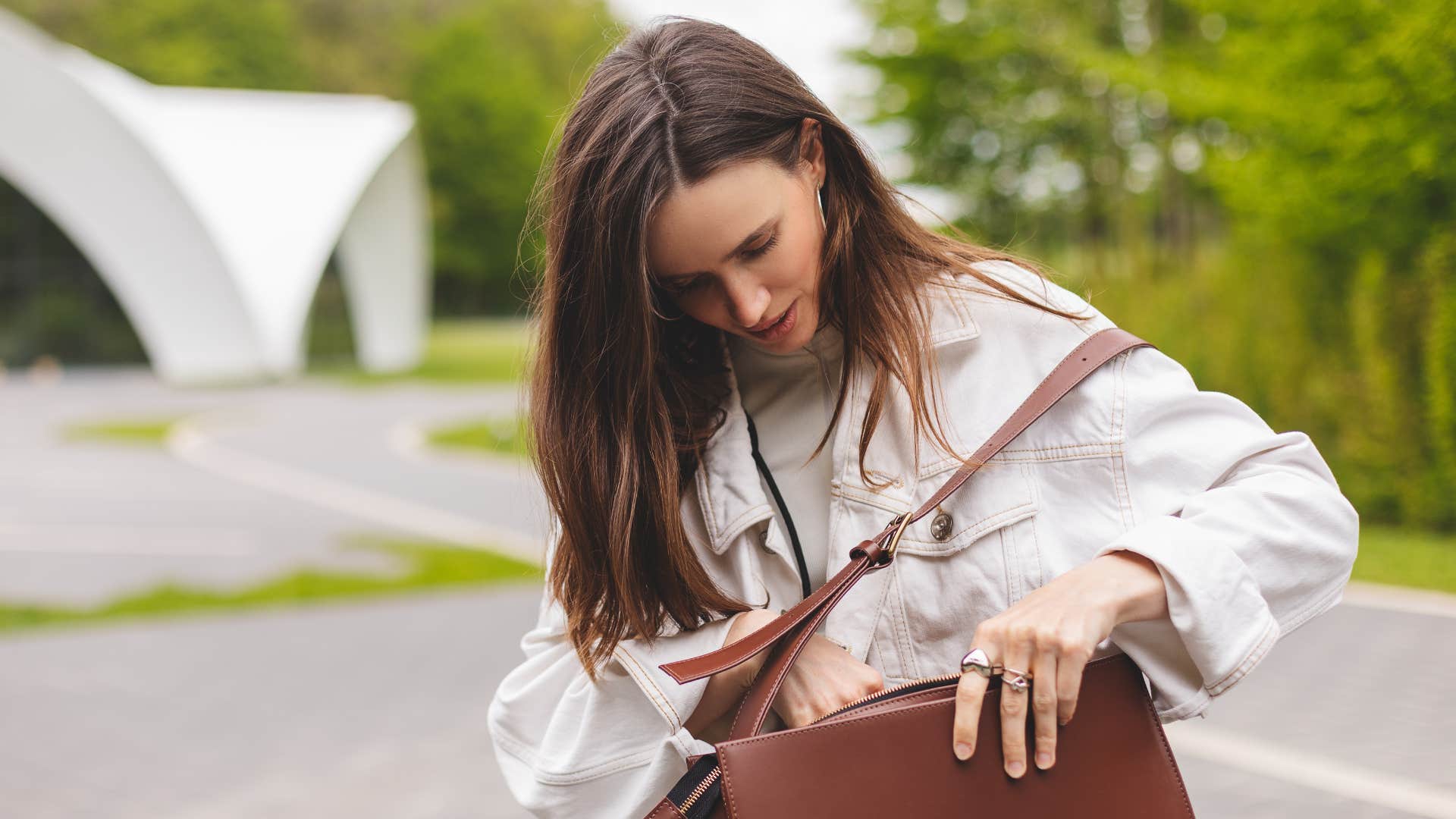 a woman looks into her designer handbag while outside