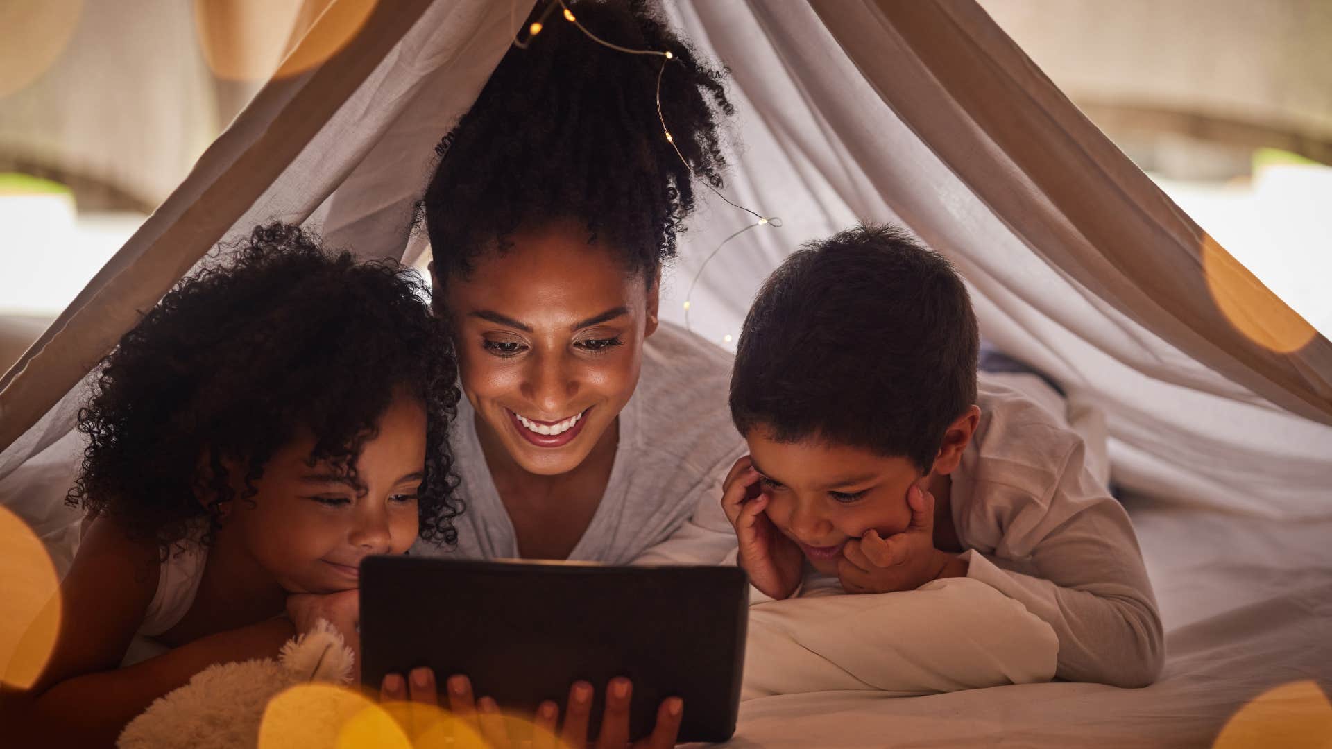 a mother watches a movie with her children on a tablet from an app she pays a monthly subscription for