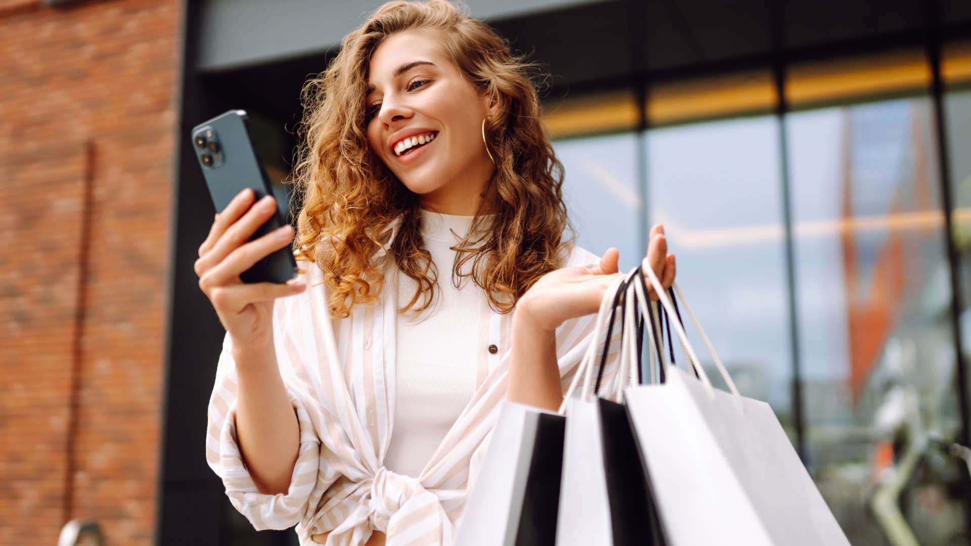 Woman buying designer clothes and holding shopping bags.