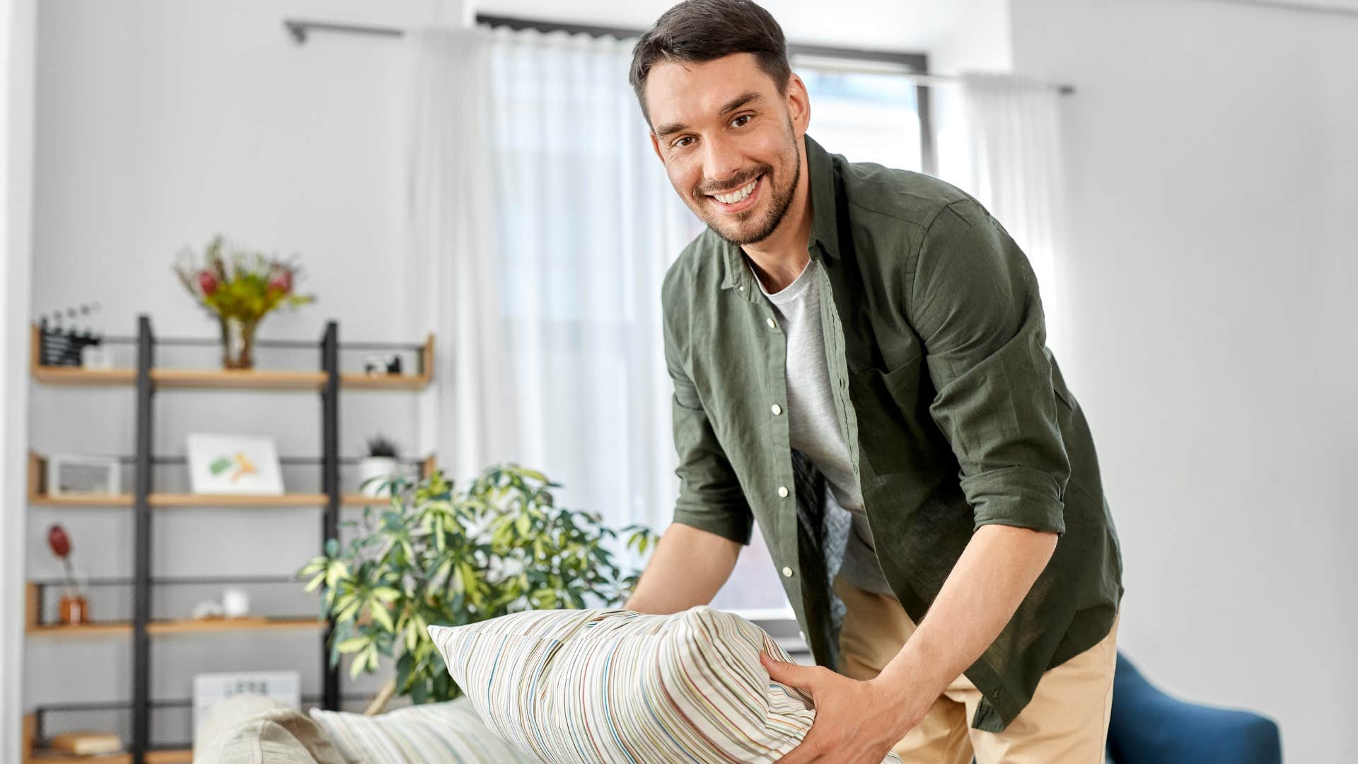 Man putting trendy home decor on his couch.