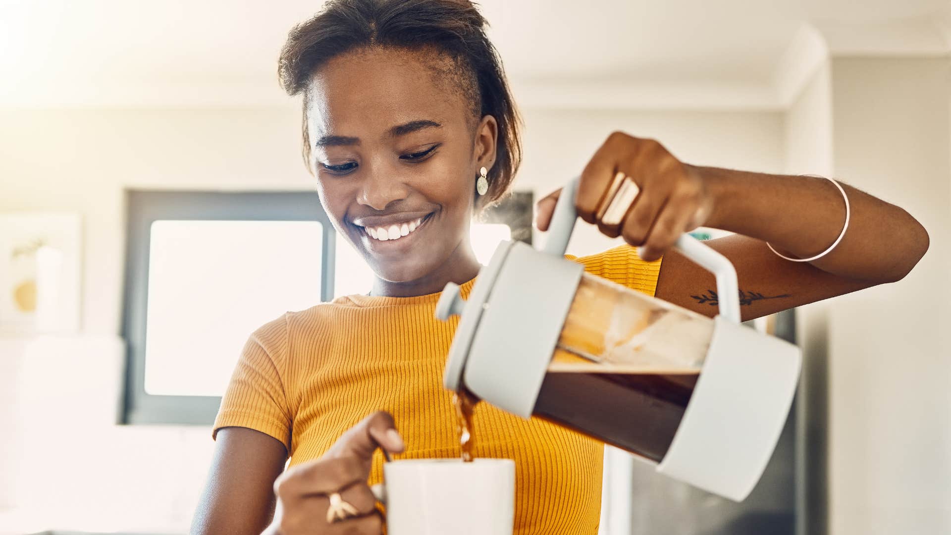 Woman sticking to a strong personal routine while pouring herself coffee.
