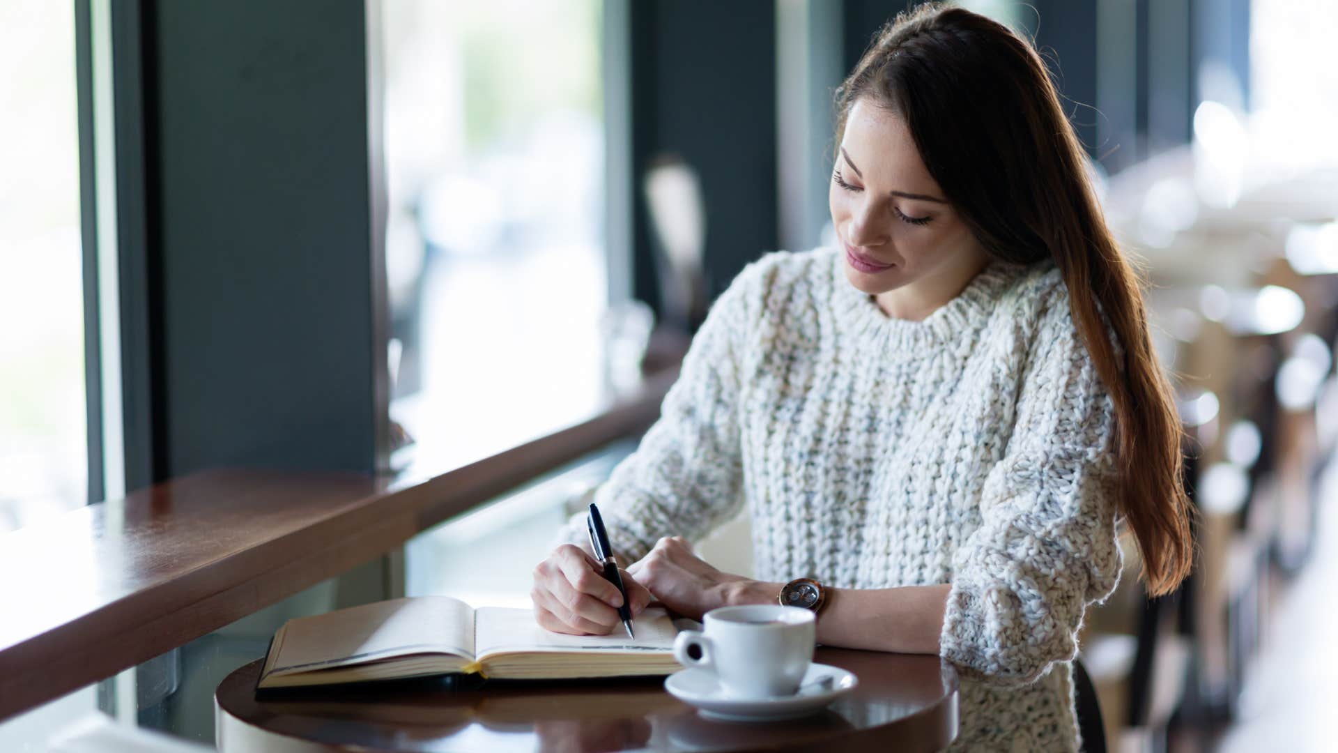 woman sitting in cafe setting weekly goals
