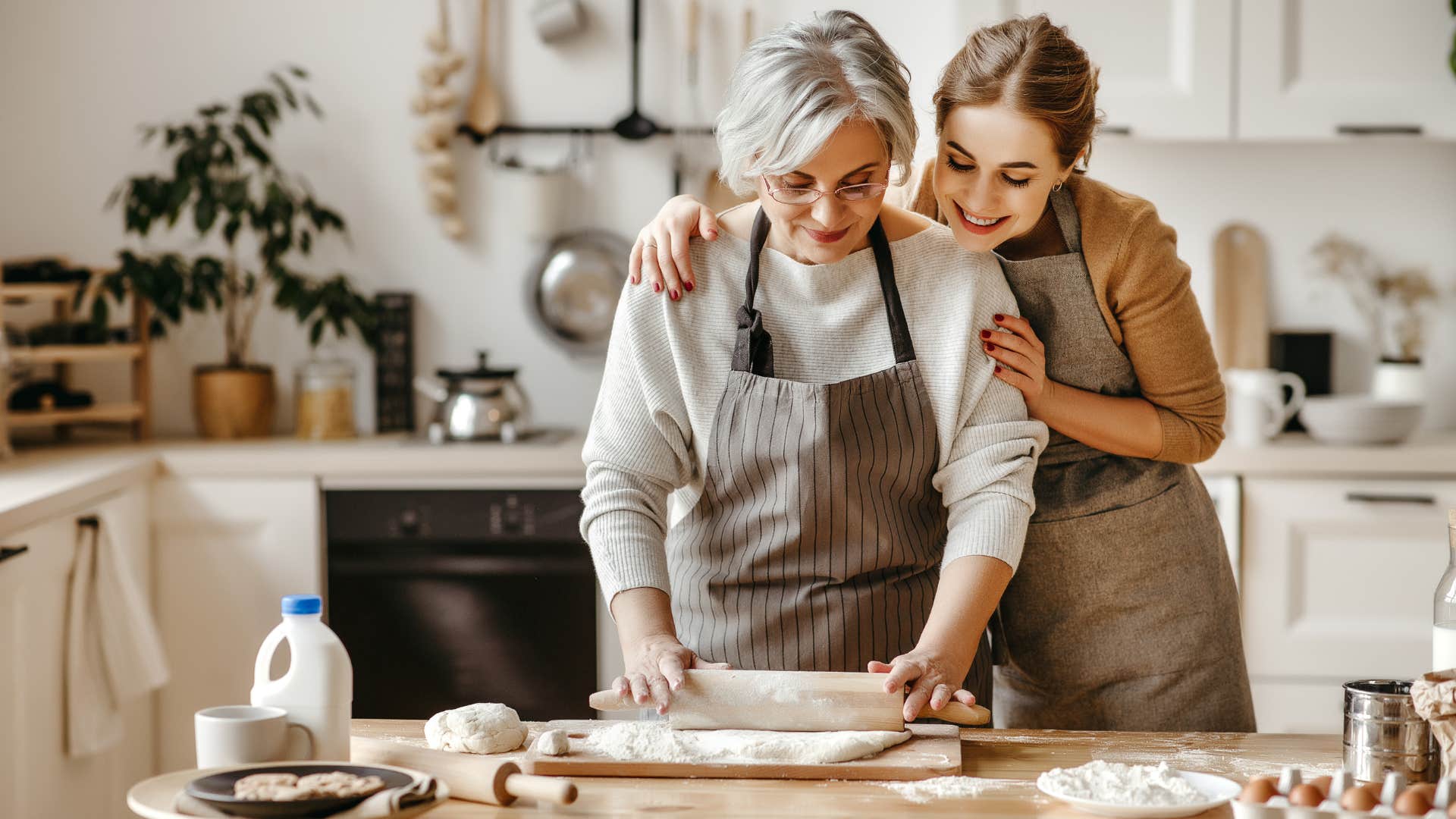 granddaughter and grandma in brown aprons cooking and baking from scratch