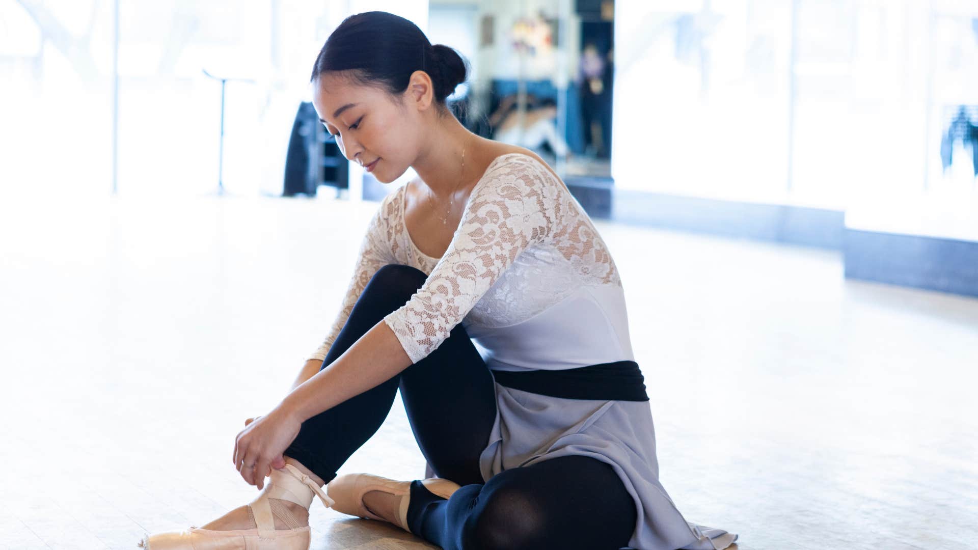 woman in ballet getup preparing to do dancing as she wraps shoes