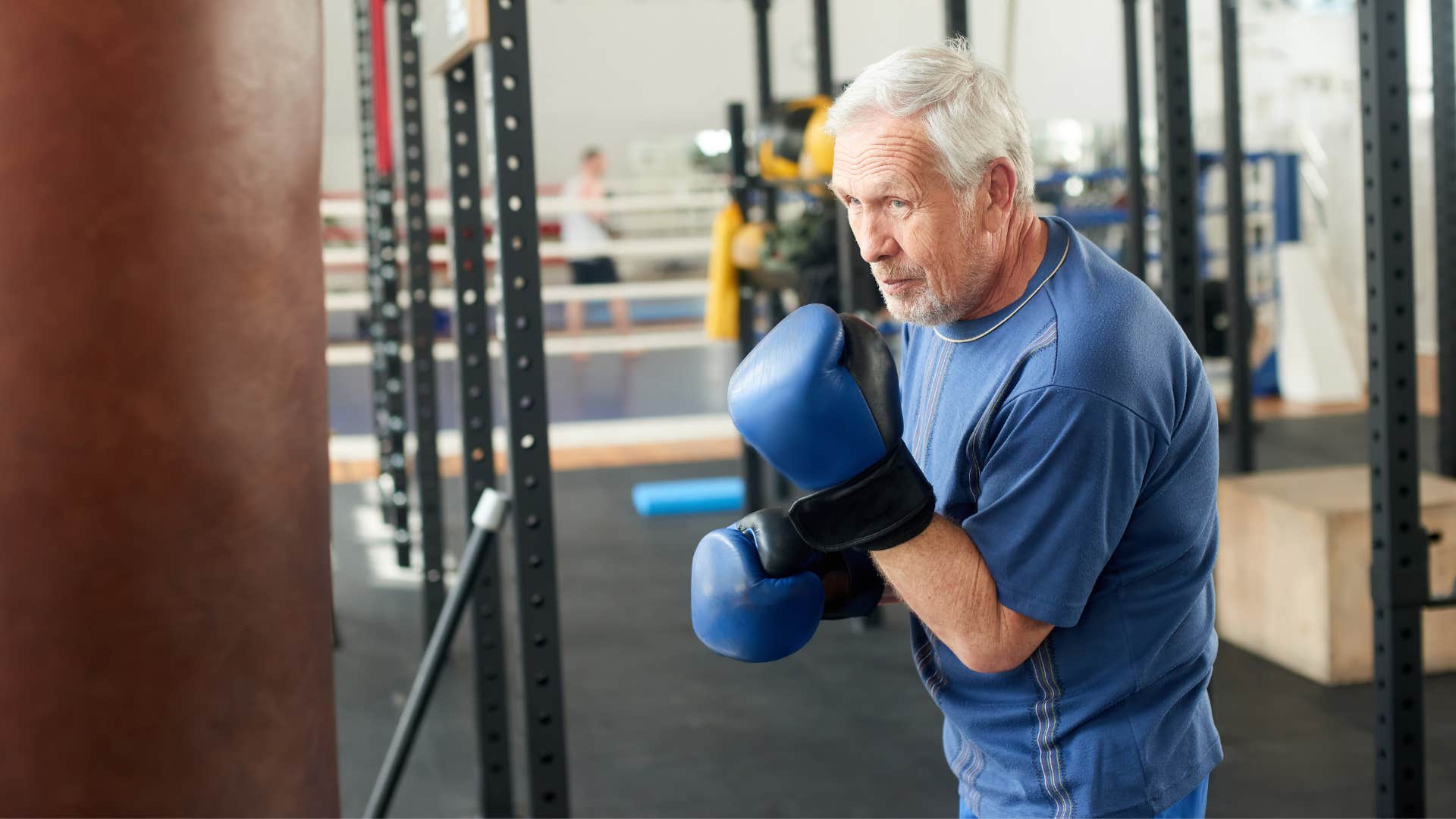 man in blue shirt boxing as he practices on bag