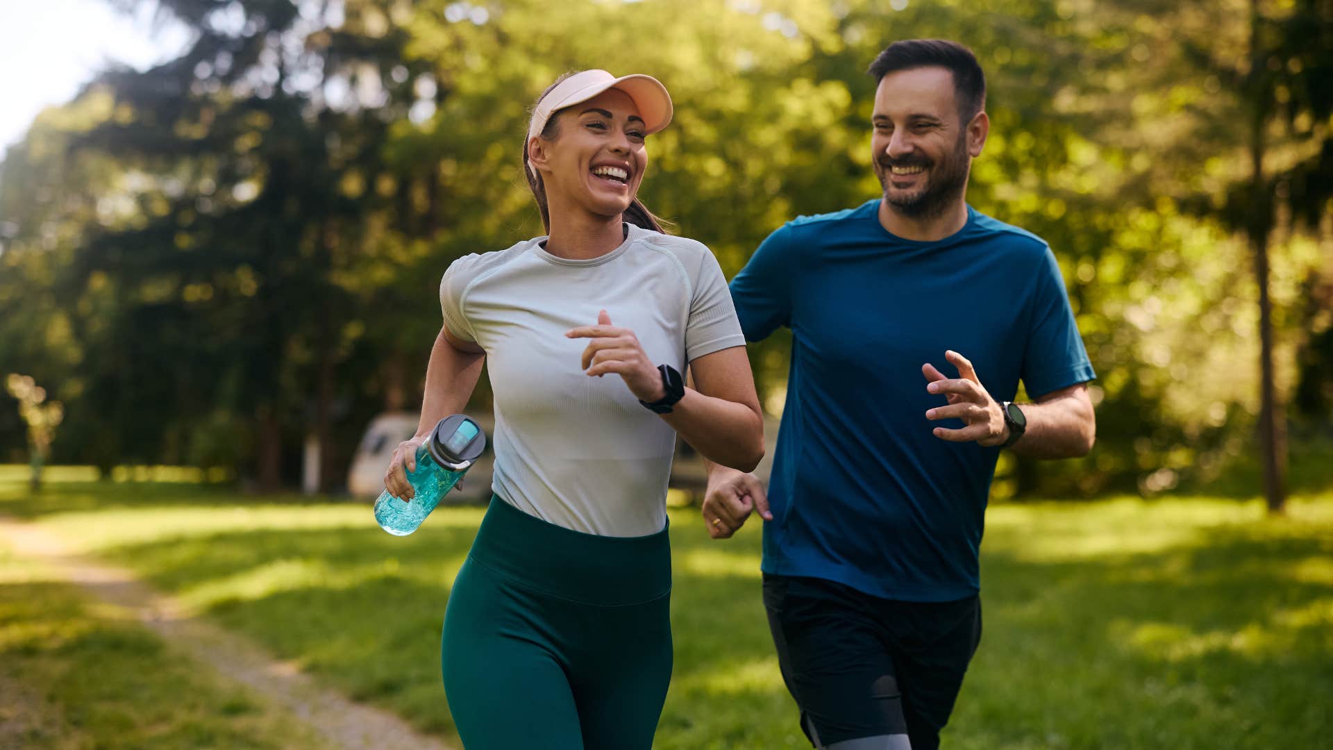 woman in white shirt and legging running with man in blue shirt as they smile