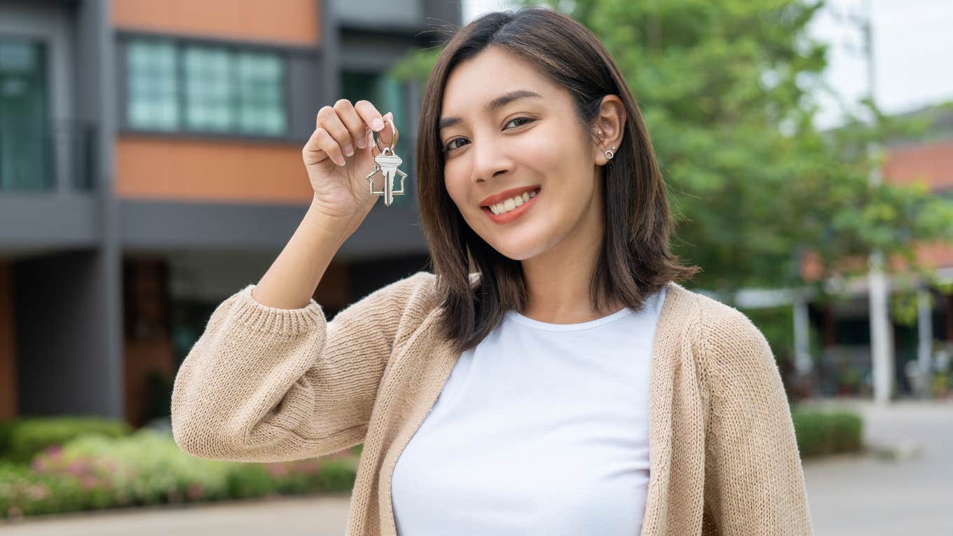 Gen Z woman holding up keys to her new home