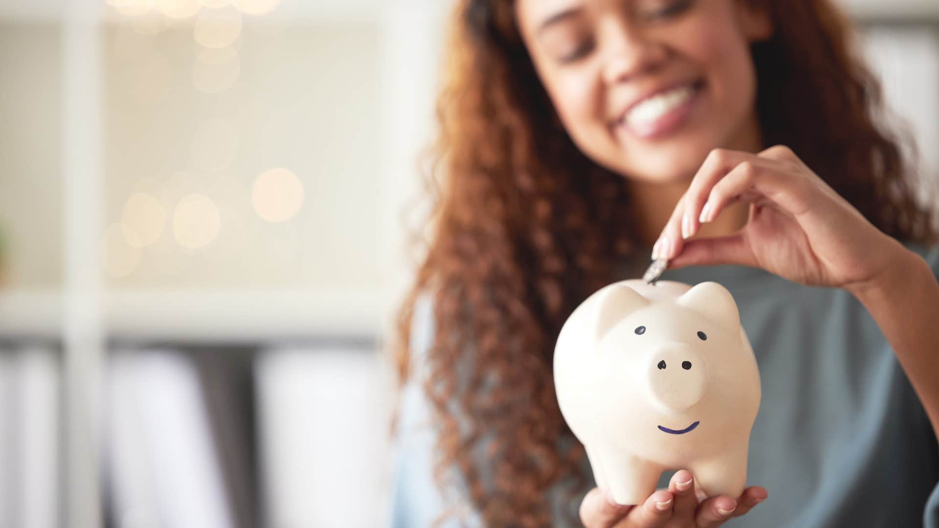 middle class woman smiling and putting money in a change jar