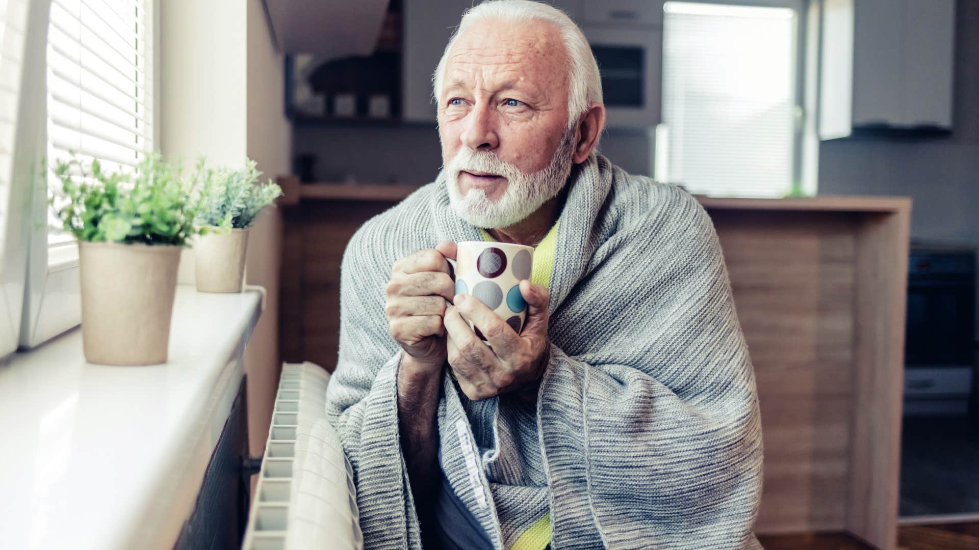 older middle class man cuddled up in winter blanket