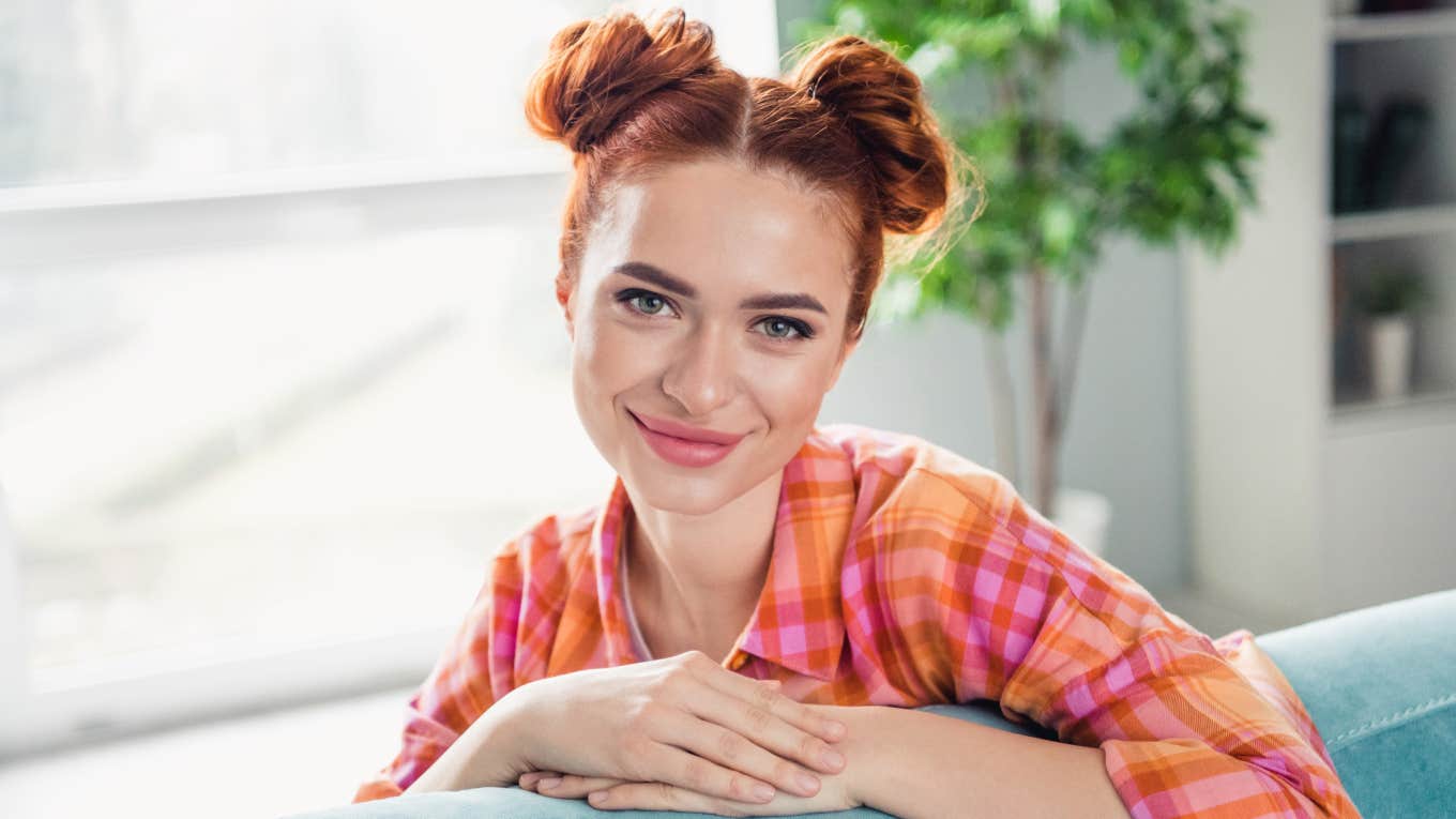 young middle class woman smiling sitting on inexpensive furniture
