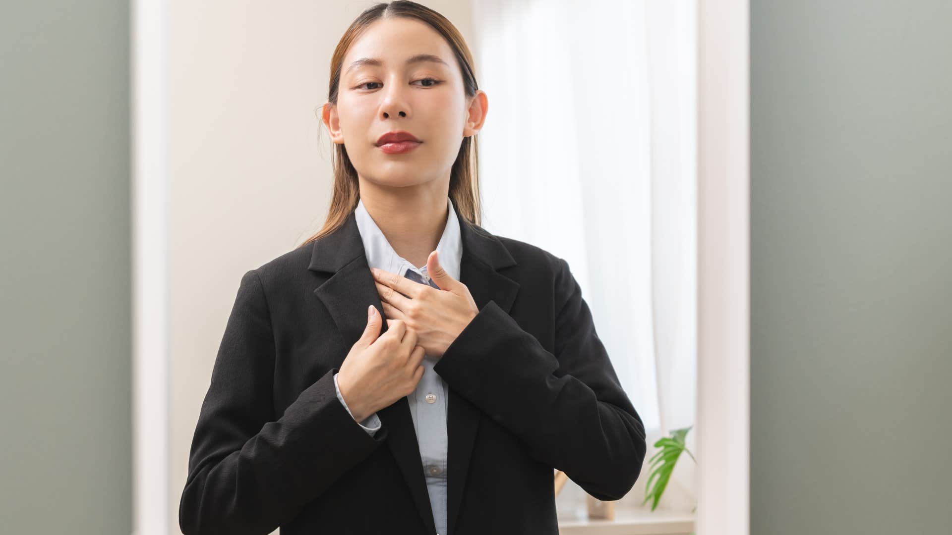 woman getting ready for work looking in the mirror