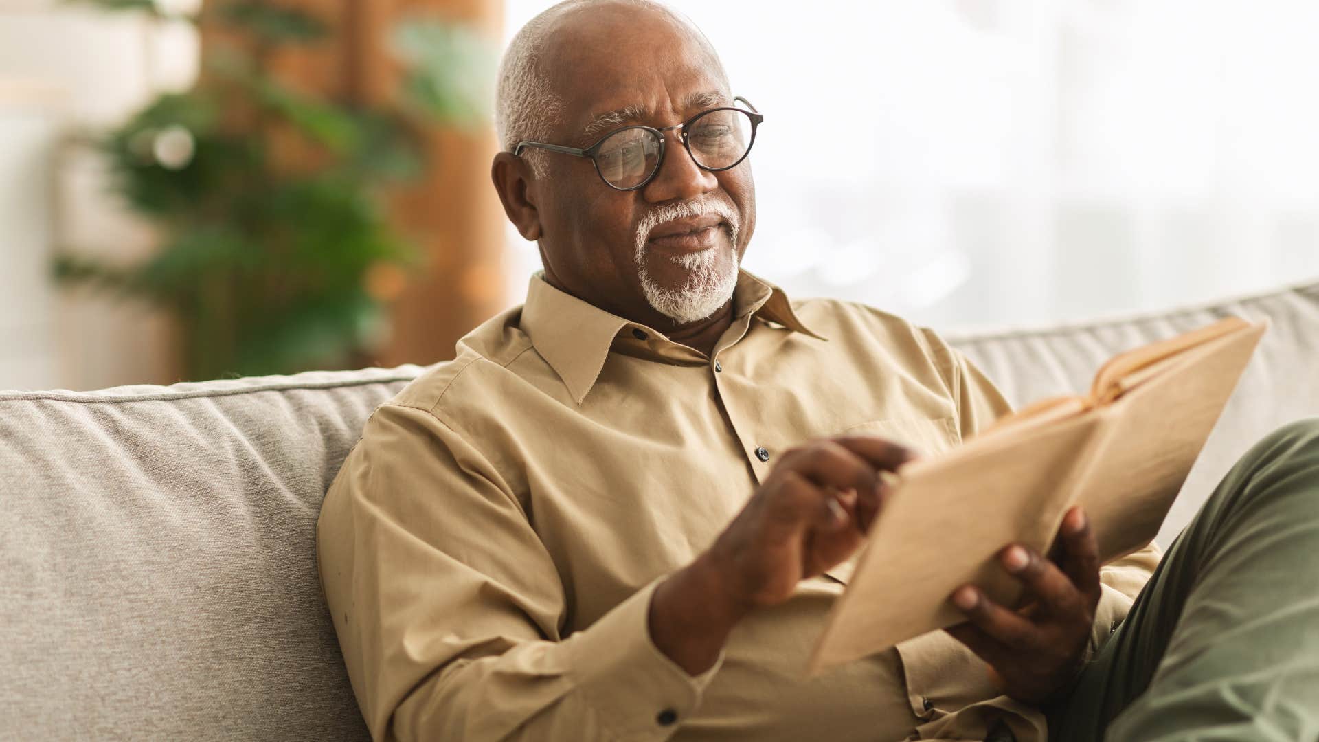 older man reading regularly on his couch