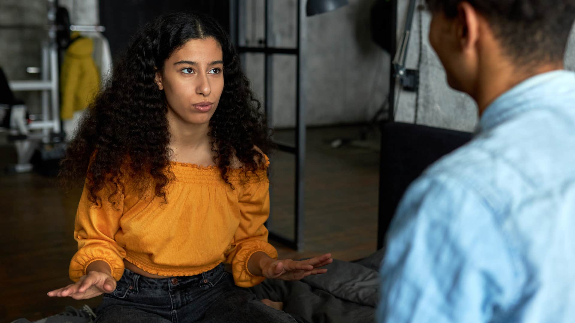 woman in orange top looking for fairness in every situation as she talks to man in blue shirt