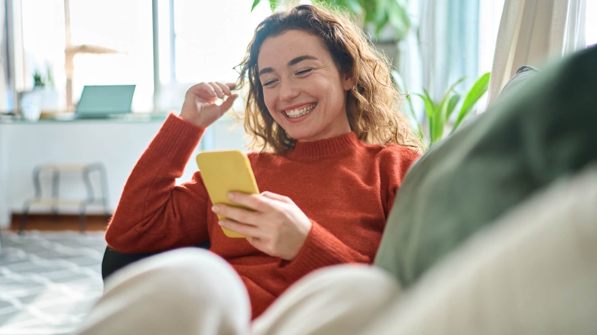 woman in red shirt smiling and looking at phone as she follows every trend or challenge