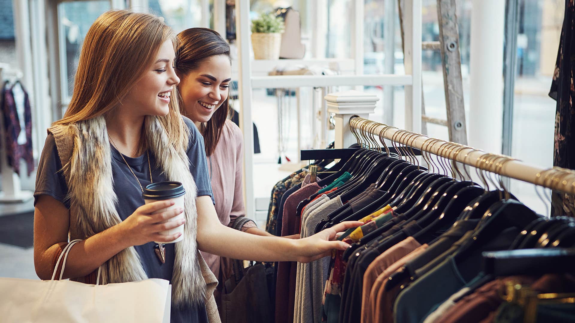two friends wearing outward status symbols of luxury as they look through clothes together