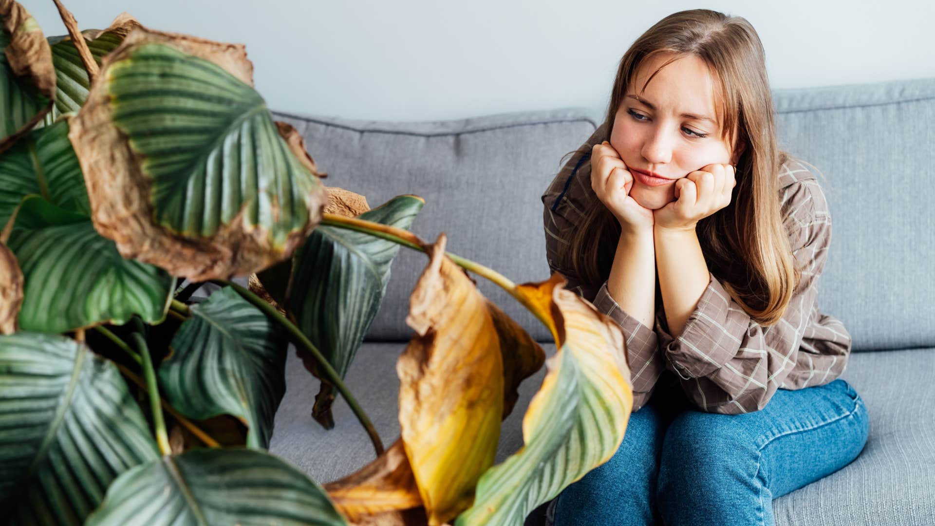 unhappy woman sitting with dead plants at home