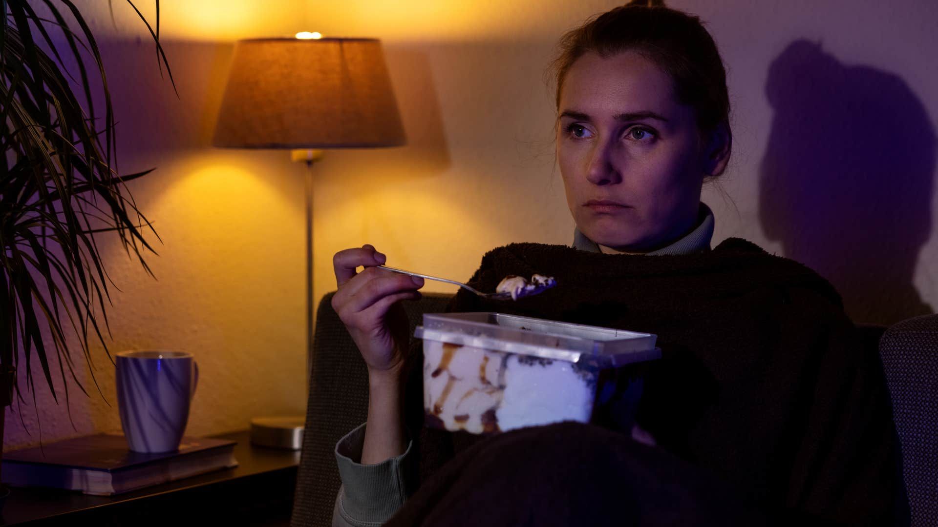 unhappy woman eating sugar on her couch at home