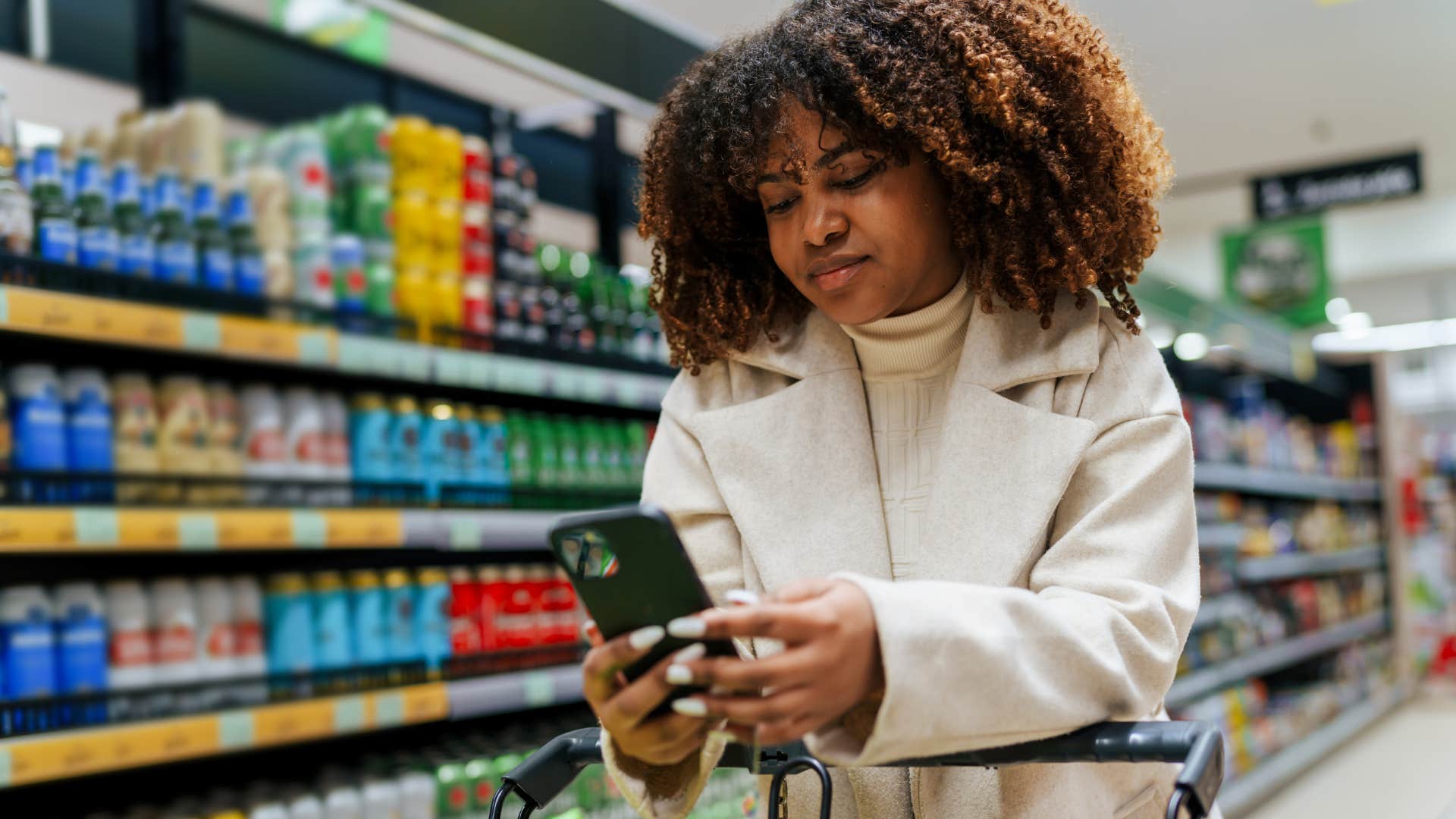 Woman who's never shopping when they're hungry looking at her phone.