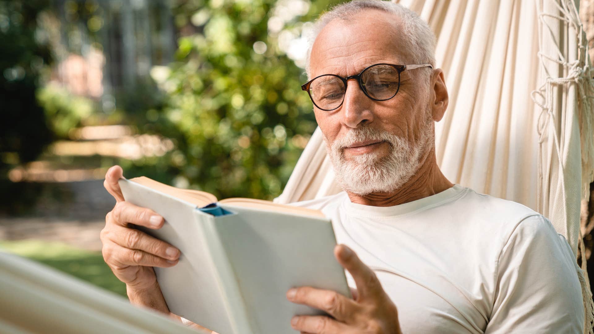 man reading books in a hammock at home
