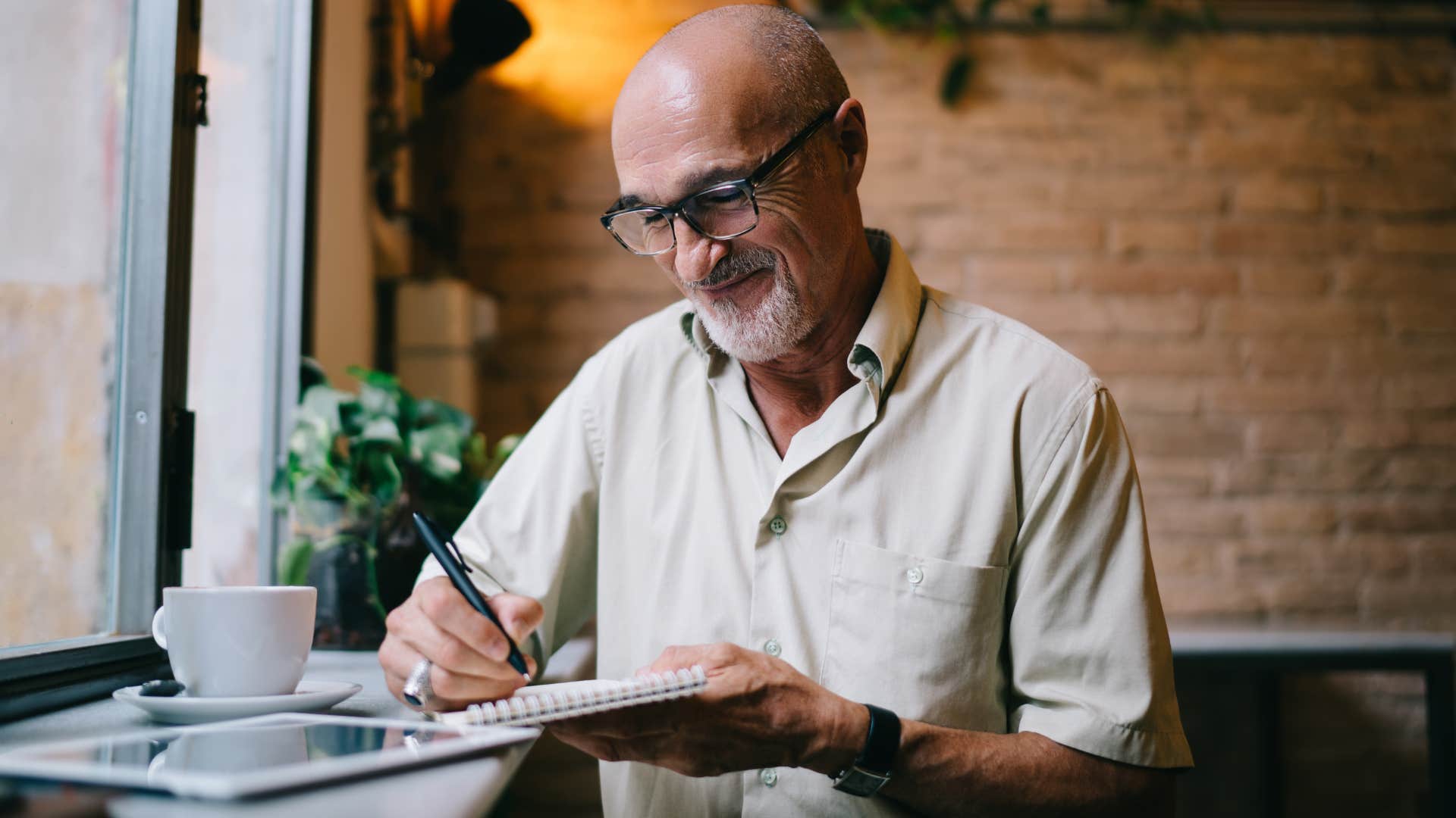 good man writing in a journal at home