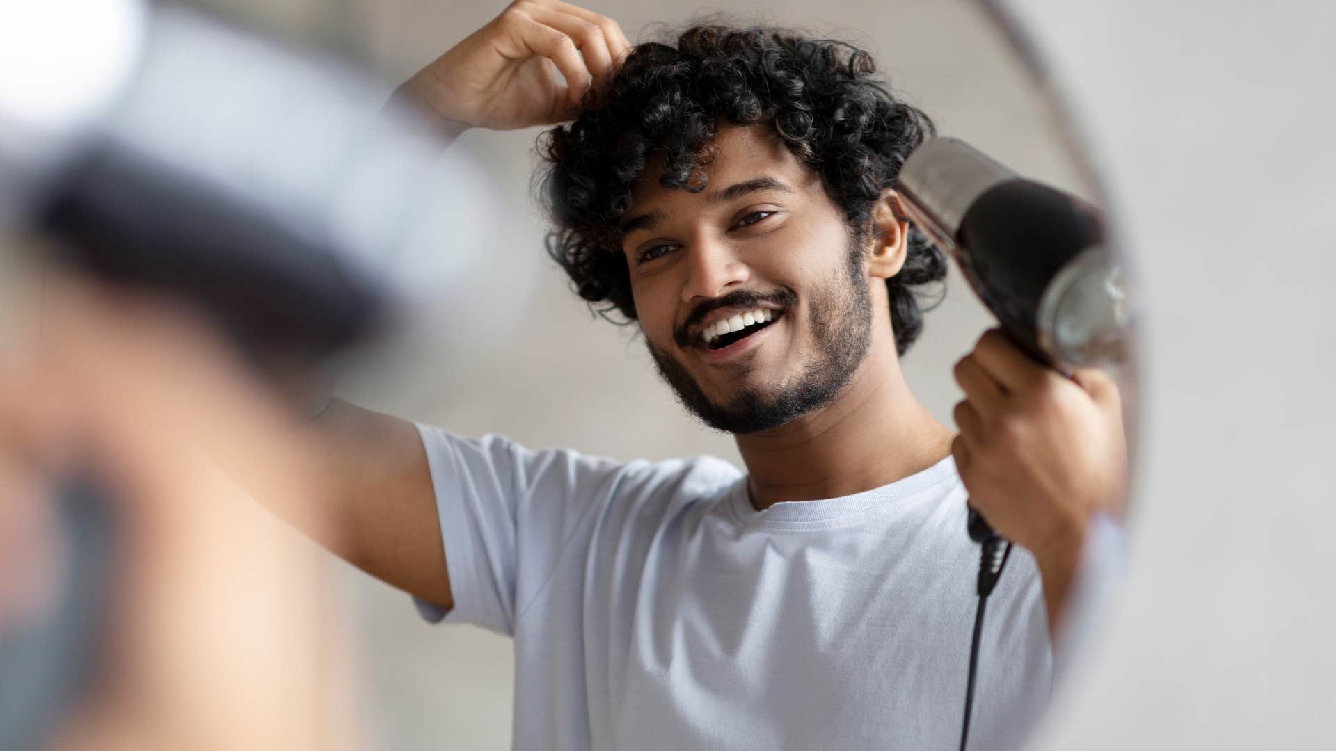 man blow drying his hair after using shampoo and conditioner