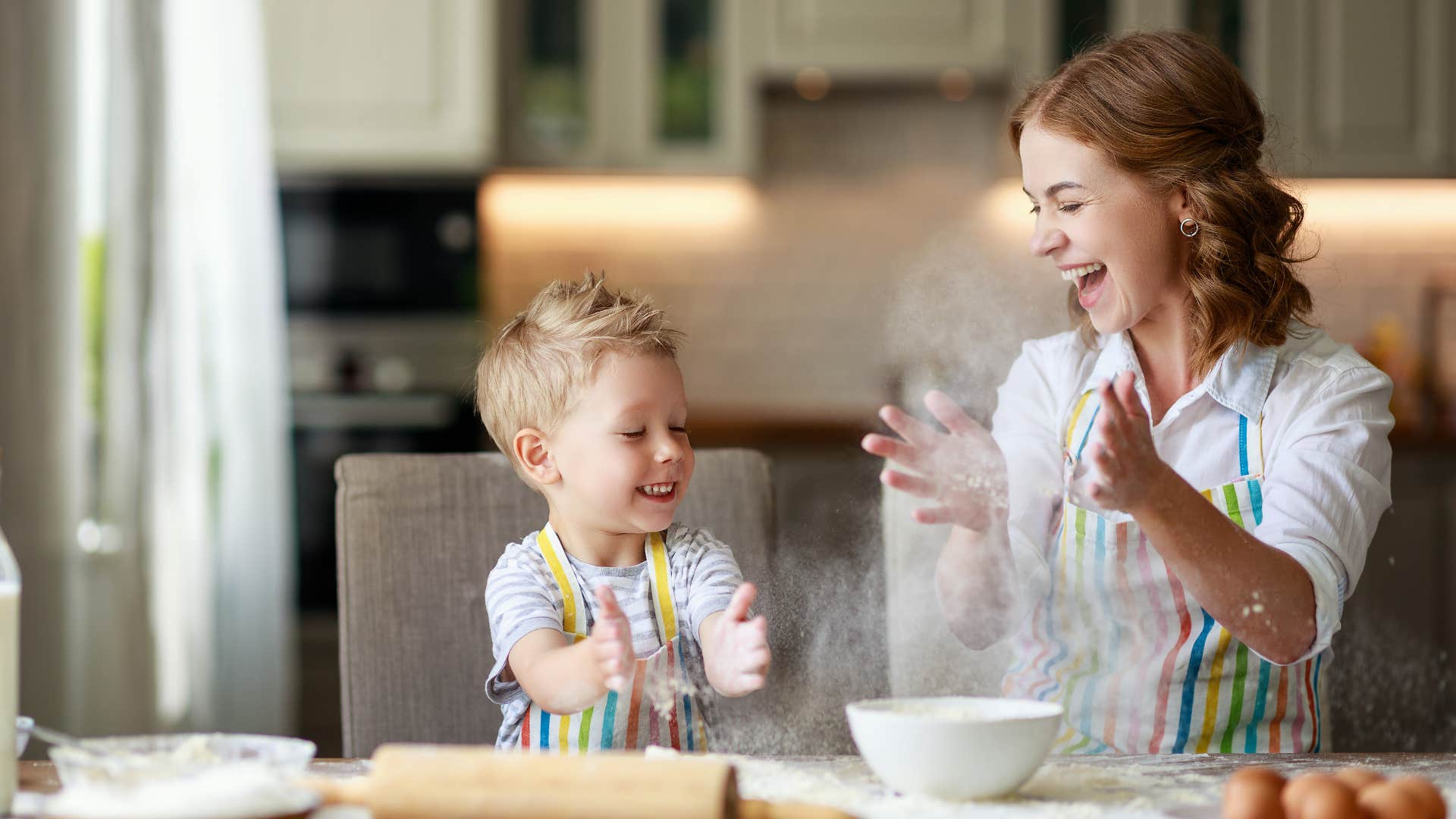 a mother helps her son use a rolling pin