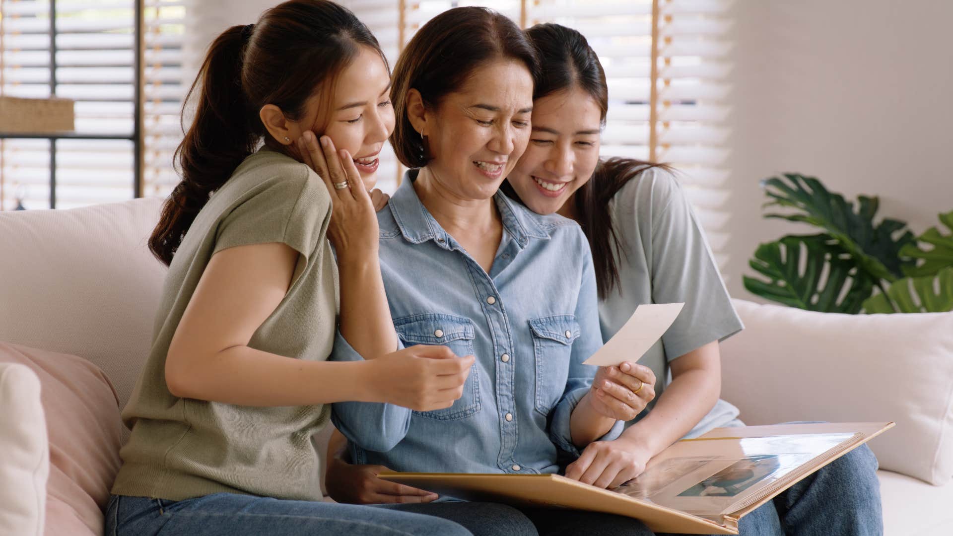 a mother and her daughters look over their family photos together