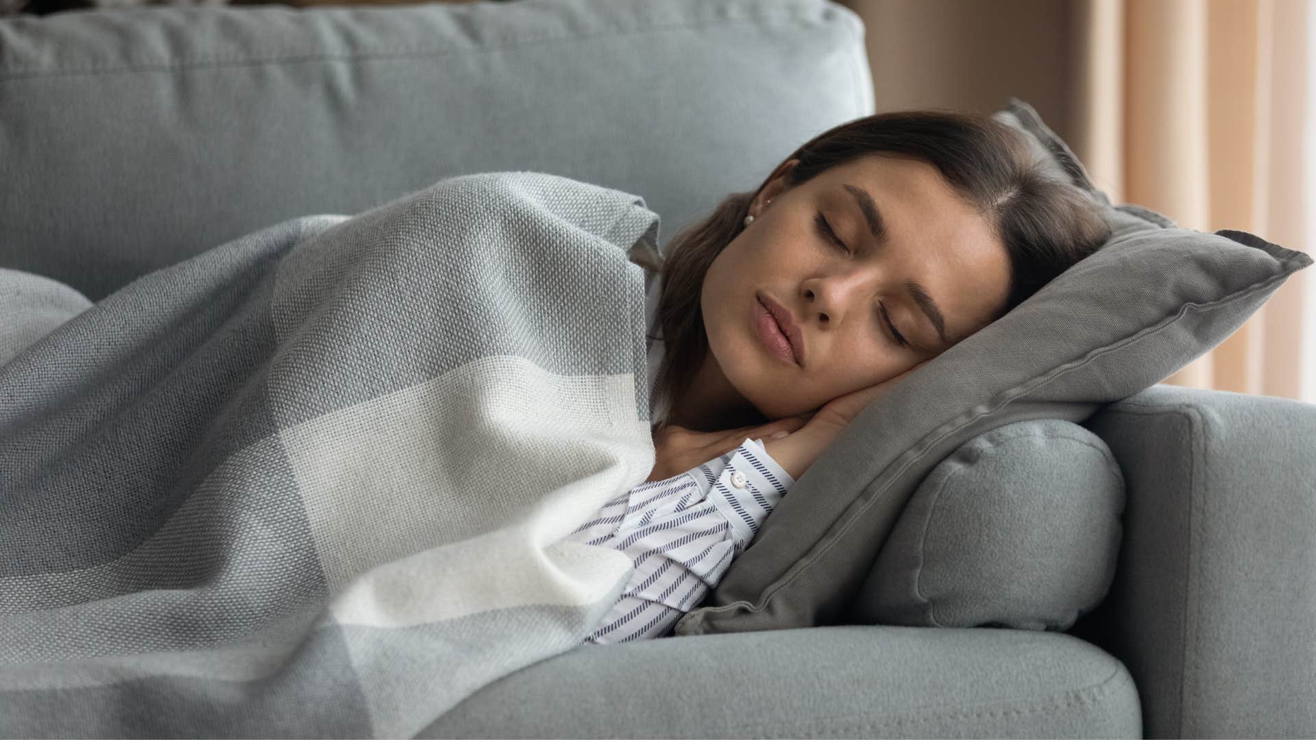 sleeping woman wrapped in blanket on couch